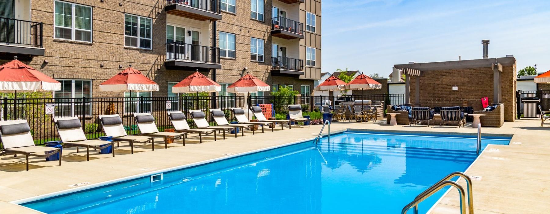 a pool with chairs and umbrellas by a building