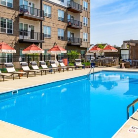 a pool with chairs and umbrellas by a building